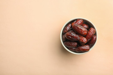 Bowl with sweet dried date fruits on color background, top view. Space for text