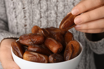 Woman holding bowl with tasty dried date fruits, closeup