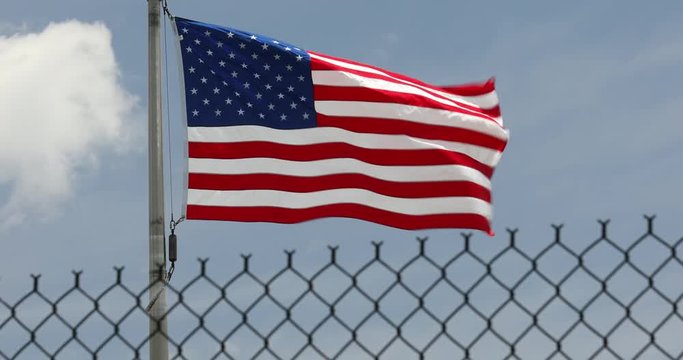USA flags fly in the wind protected by a border protection fence