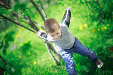 A little boy of 3 years old is playing outside. Active games with children in the spring. Happy smiling child with family in the background.