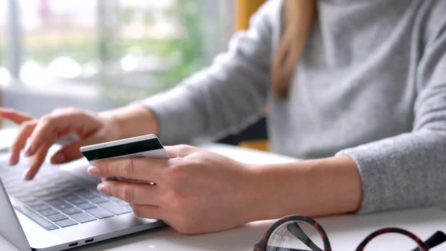 Woman makes online payment at home with a credit card and laptop