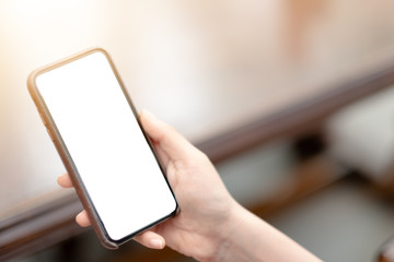 close-up on hand holding phone showing white screen on desk at coffee shop.