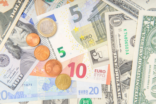 group of coins on background of various Euro and Dollar banknotes