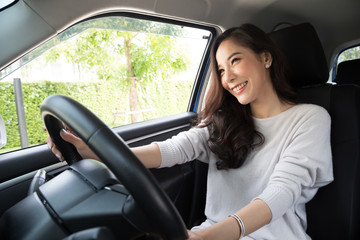 Obraz na płótnie Canvas Asian women driving a car and smile happily with glad positive expression during the drive to travel journey, People enjoy laughing transport and relaxed happy woman on roadtrip vacation concept