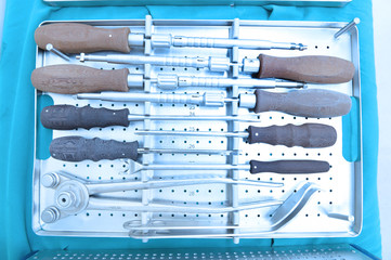 Detail shot of steralized surgery instruments with a hand grabbing a tool take with art lighting and blue filter
