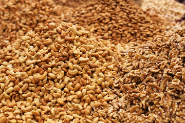 Roasted salted cashews, raw walnuts and almonds, lying on a large counter at the market in Deira, Dubai.