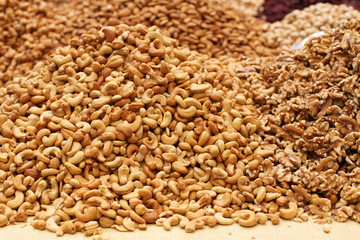 Roasted salted cashews, raw walnuts and almonds, lying on a large counter at the market in Deira, Dubai.