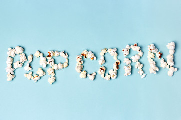 Inscription popcorn on a blue background close-up, top view