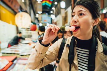cheerful woman trying dango in brocade market