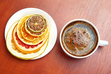 Black coffee in a white Cup surrounded by citrus dried fruits