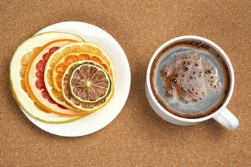 Black coffee in a white Cup surrounded by citrus dried fruits