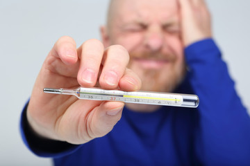man shows a thermometer with a high temperature