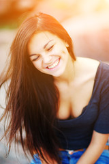 Fototapeta premium Young beautiful long-haired girl genuinely laugh, eyes closed, outdoors, close-up.