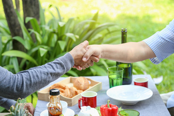Senior man have greeting by hand shaking with woman friend in the garden party, elderly retirement lifestyle concept. 