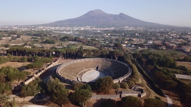 The ruins of a Roman amphitheater in Pompeii overshadow by Mount Vesuvius