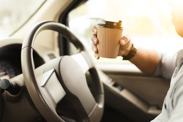 A driver drinking coffee in the car.