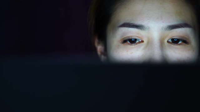 Woman working and look at computer screen at night.