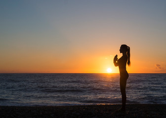 Fototapeta na wymiar Young healthy woman practicing yoga fitness exercise on the beach at sunset. Healthy lifestyle concept. Copy space text.