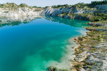 An old gypsum quarry filled with blue and pure water. Aerial view, from top to bottom