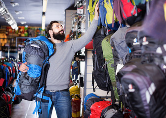 Male choosing new backpack in sports equipment shop
