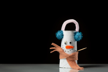 A figure of a snowman made of a toilet paper roll by a child