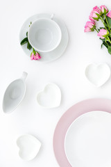 Empty white and pink colorful plate and roses for table setting on white table backgroung top view copy space