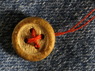 Old wooden button on jeans so close