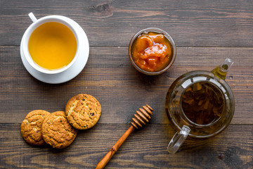 Tea with homemade cookies. Fresh cookies, cup of tea, teapot on dark wooden background top view