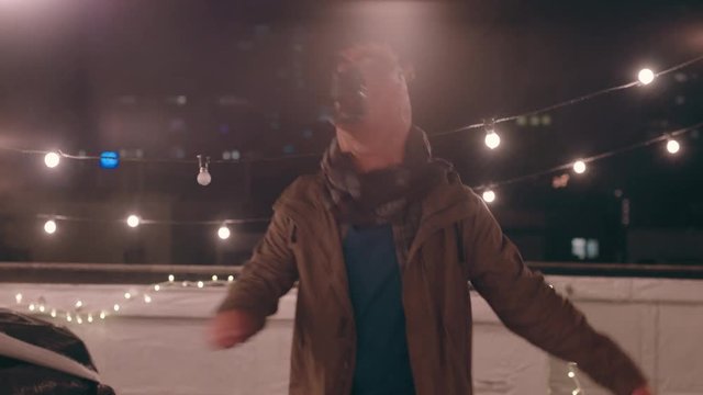 funny man wearing horse mask dancing in rain on rooftop at night having fun performing silly dance moves celebrating weekend