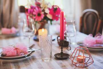 summer cottage kitchen decorated for festive dinner. Romantic table setting with candles and flowers in rustic style.