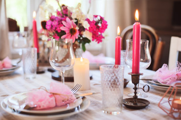 summer cottage kitchen decorated for festive dinner. Romantic table setting with candles and flowers in rustic style.