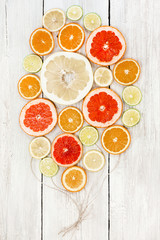 Fresh bright juicy citrus sliced and collected together with craft ropes as balloons. In white wood background. lemon, orange, lime, grapefruit, sweetie, pomelo, oroblanco