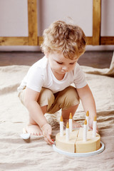 Child boy playing in his room with a wooden toy cake
