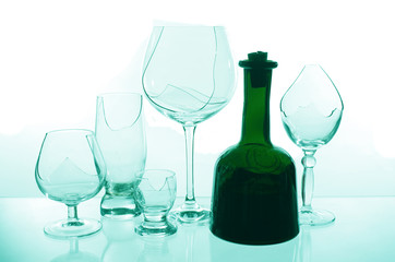 A bottle of wine on the background of broken glasses on a light background