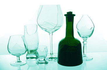 A bottle of wine on the background of broken glasses on a light background