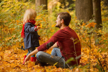 Father and daughter hug in autumn park.