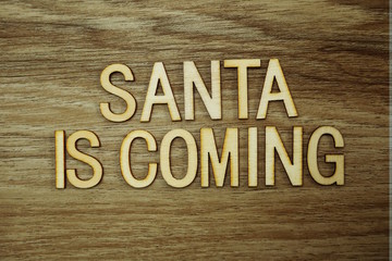Santa Is Coming text message on wooden background