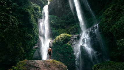 A man stands on the stone on the background waterfall Bali Indonesia
