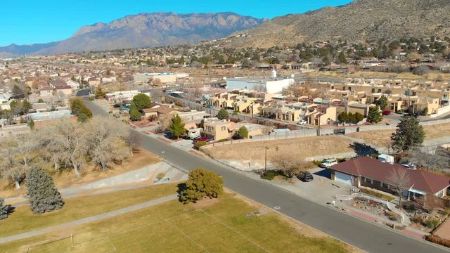 This is a flyover shot over a park and houses towards a pretty busy street.