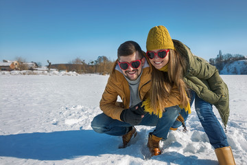 A loving couple of young people are laughing at the camera. Winter sunny day.