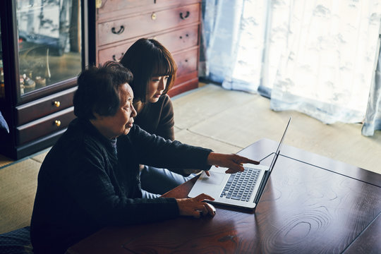 Senior and young woman using laptop together