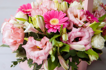 Flower arrangement bouquet of rose, alstroemeria, gerbera, in a pink basket on a gray wooden background.