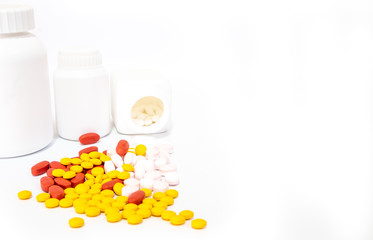 Red, Yellow,Pink tablets and white medicine bottles placed on a white background, Medical concept