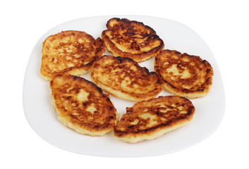 Six homemade fried cottage cheese pancakes on a white plate isolated