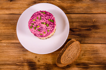 White plate with russian traditional new year salad herring under fur coat and rye bread on wooden table. Top view