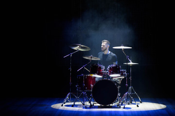 Obraz na płótnie Canvas Silhouette drummer on stage. Dark background, smoke spotlights