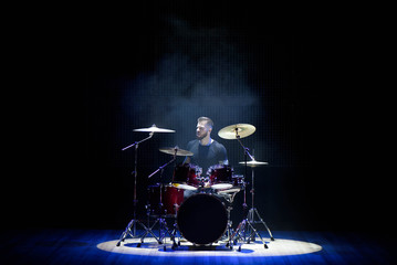 Fototapeta na wymiar Silhouette drummer on stage. Dark background, smoke spotlights
