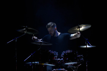 music, people, musical instruments and entertainment concept - male musician with drumsticks playing drums and cymbals at concert or studio