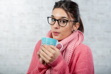 young brunette woman dressed in pink drinking a cup of tea