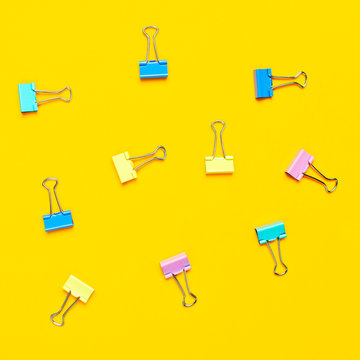 Multicolored paper clips on bright yellow background top view flat lay copy space. Minimalistic office background, education, objects for creativity. Back to school concept.